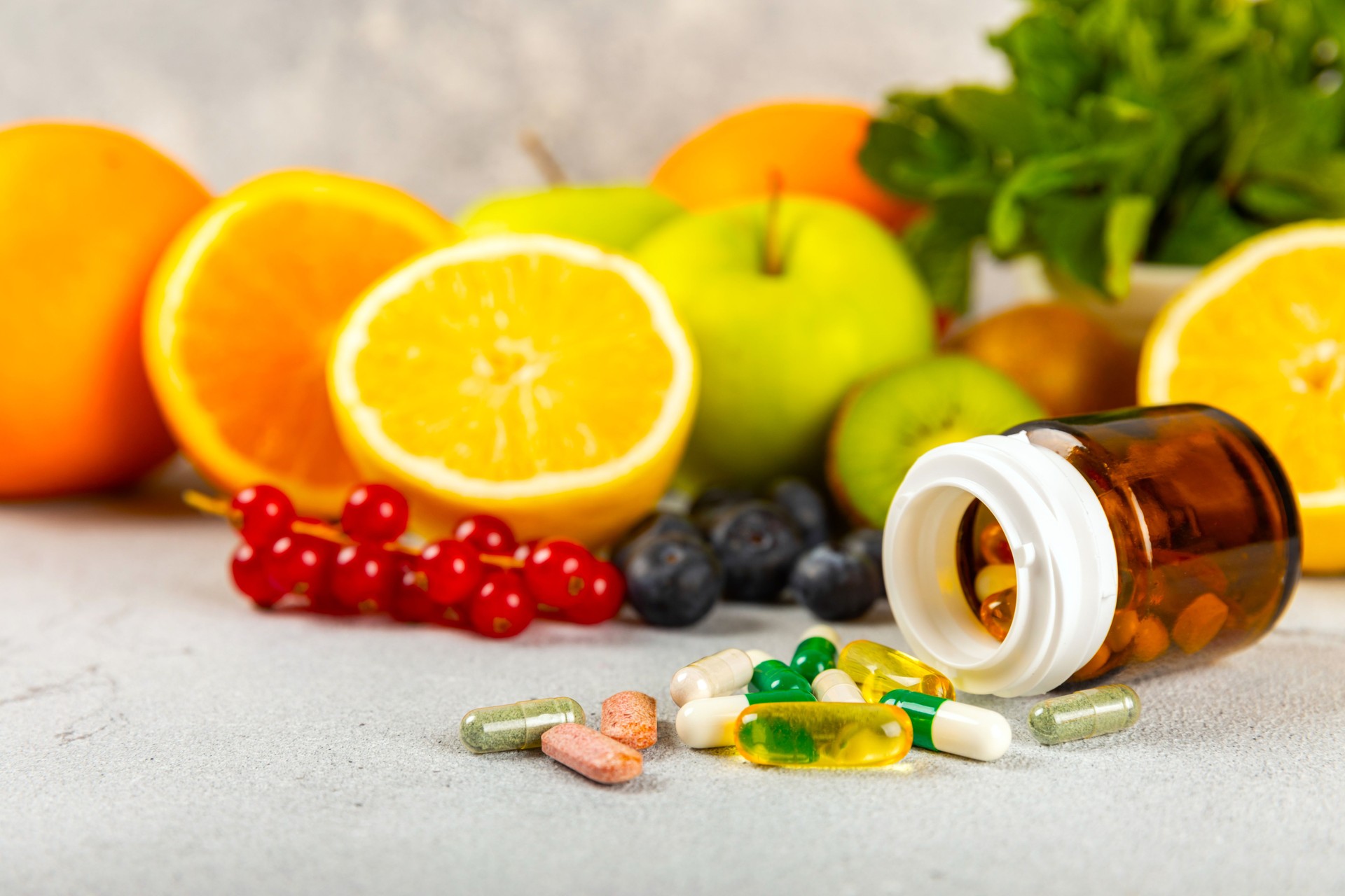 Vitamins and supplements. Variety of vitamin tablets in a jar on a texture background.Multivitamins with fresh and healthy fruits.Food supplements. Flat lay. Space for text.Copy space